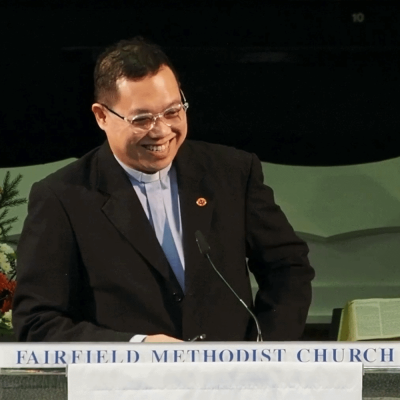 Smiling pastor at Fairfield Methodist Church sermon, church service, Christian worship, leadership.