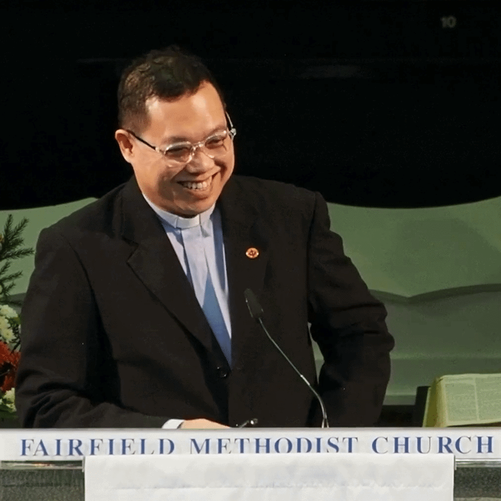 Smiling pastor at Fairfield Methodist Church sermon, church service, Christian worship, leadership.
