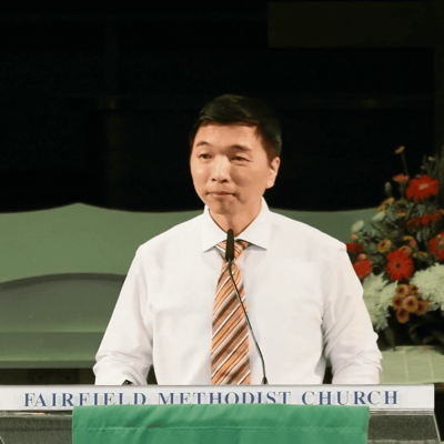 Serious man speaking at Fairfield Methodist Church pulpit during sermon.