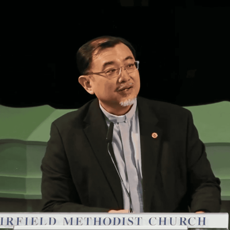 Thoughtful pastor delivering a sermon at Fairfield Methodist Church in Singapore.